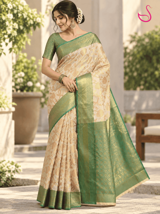 Cream and gold saree with intricate floral weave, green and gold zari border and elegant pallu, styled with a green brocade blouse in a front pose.