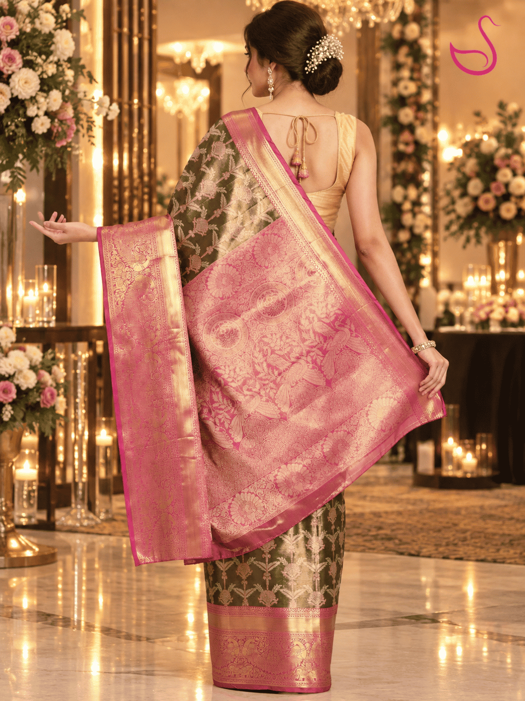 Woman shown from the back wearing a dark olive-green and pink-gold brocade saree, highlighting the richly woven pink-gold pallu and blouse back, posed in a luxurious reception setting with warm lighting, floral décor and candles. Ishaana Ethnics emblem appears in the top-right corner.