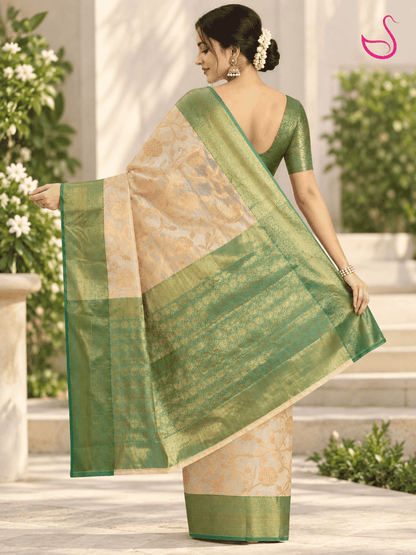 Cream and gold saree with intricate floral weave and green-gold zari pallu, styled with a green brocade blouse in an elegant back pose.