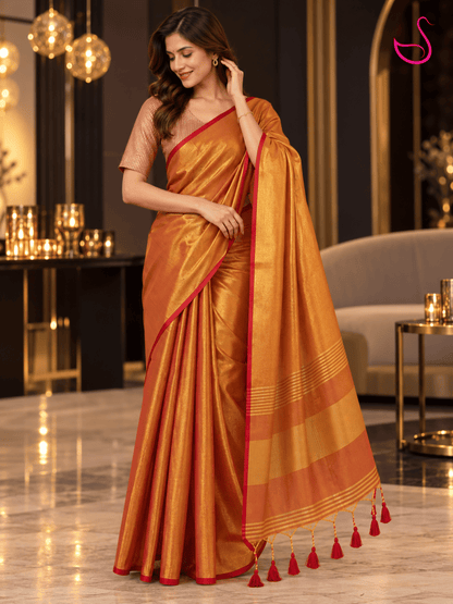 Golden-orange silk saree with red border and striped blouse, styled for a festive occasion