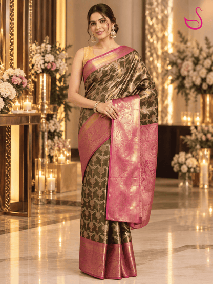 Elegant woman wearing a dark olive-green and pink-gold brocade saree with an ornate zari pallu, posed in a luxurious reception setting with warm lighting, floral décor and candles. Ishaana Ethnics emblem appears in the top-right corner.
