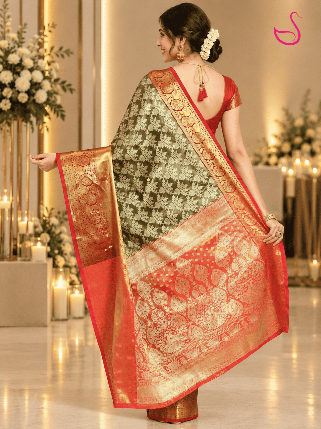 woman shown from the back wearing an black tissue silk saree with intricate gold motifs and an elaborate red-orange and gold zari pallu, paired with a red blouse and traditional jewellery, highlighting the saree’s detailed pallu design.