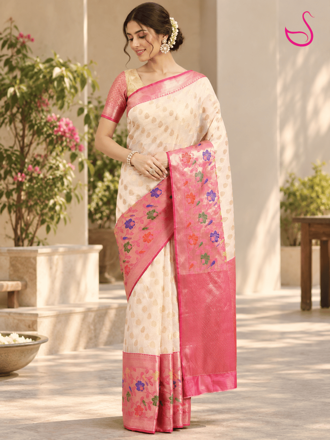 Cream woven saree with pink floral zari pallu and pink woven blouse, styled on a woman outdoors